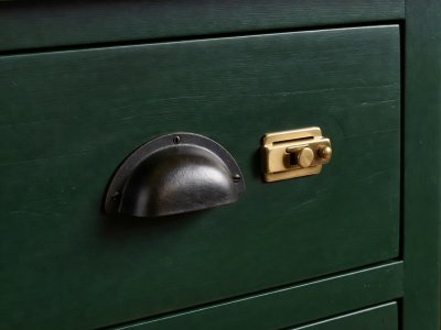 Beeswaxed cast iron cup pull and brass latch on a deep forest green painted timber drawer