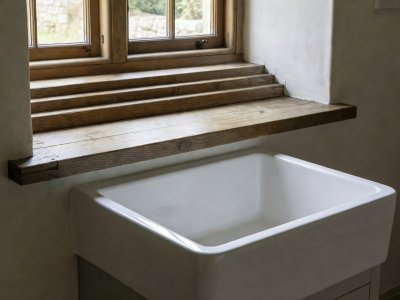 Deep ceramic sink fitted below a low cottage casement window with stepped timber upstand
