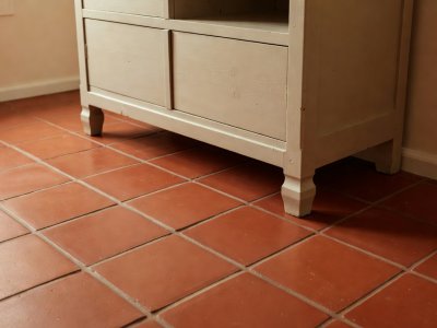Warm terracotta red quarry tile kitchen floor meeting the legs of a painted pine Welsh dresser